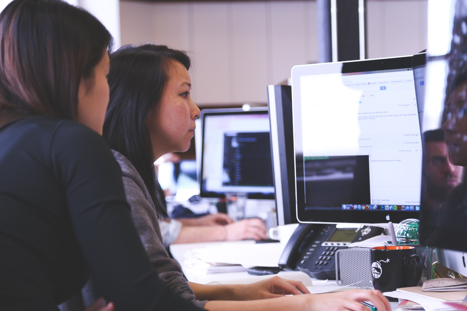 Two colleagues working together at a desk in an Asian office