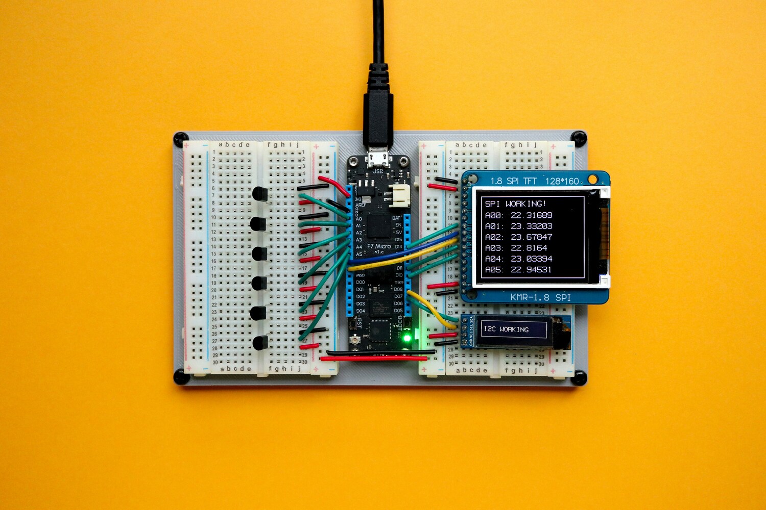 Microcontroller on breadboard with colored wires and small display screens