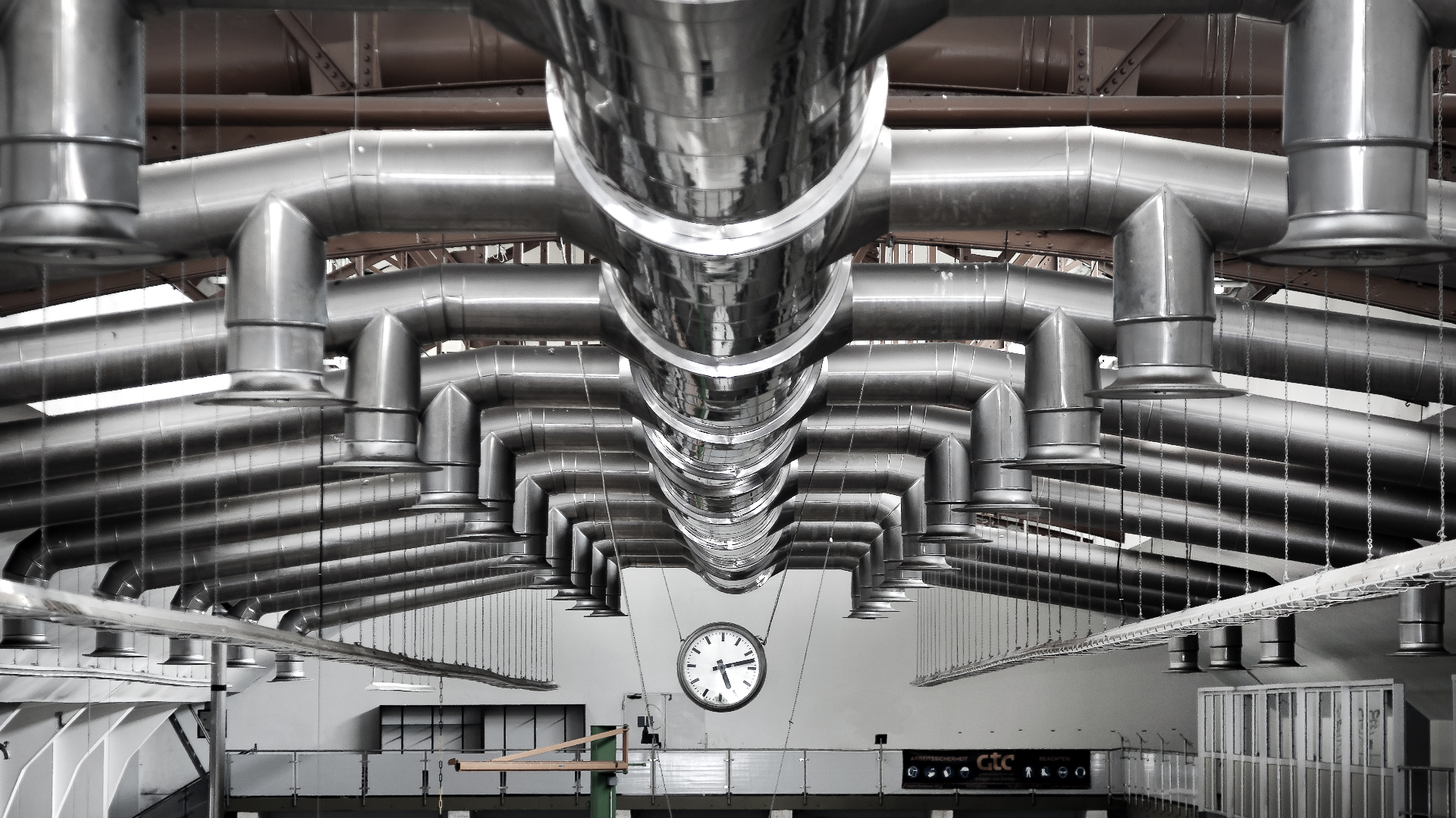 Industrial ventilation and air treatment ductwork suspended from the ceiling of a manufacturing facility