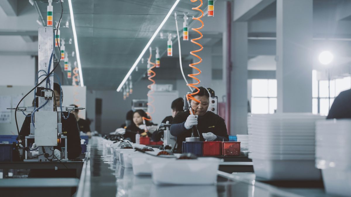 Factory floor with workers assembling components at production stations